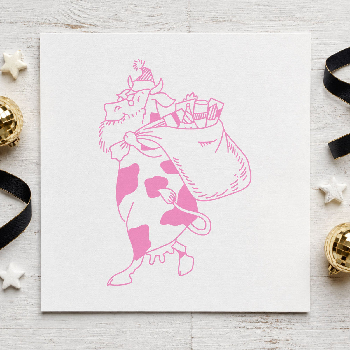 Santa Cow with Gift Sack Rubber Stamp Large impression in pink ink on white paper in a styled craft setting.