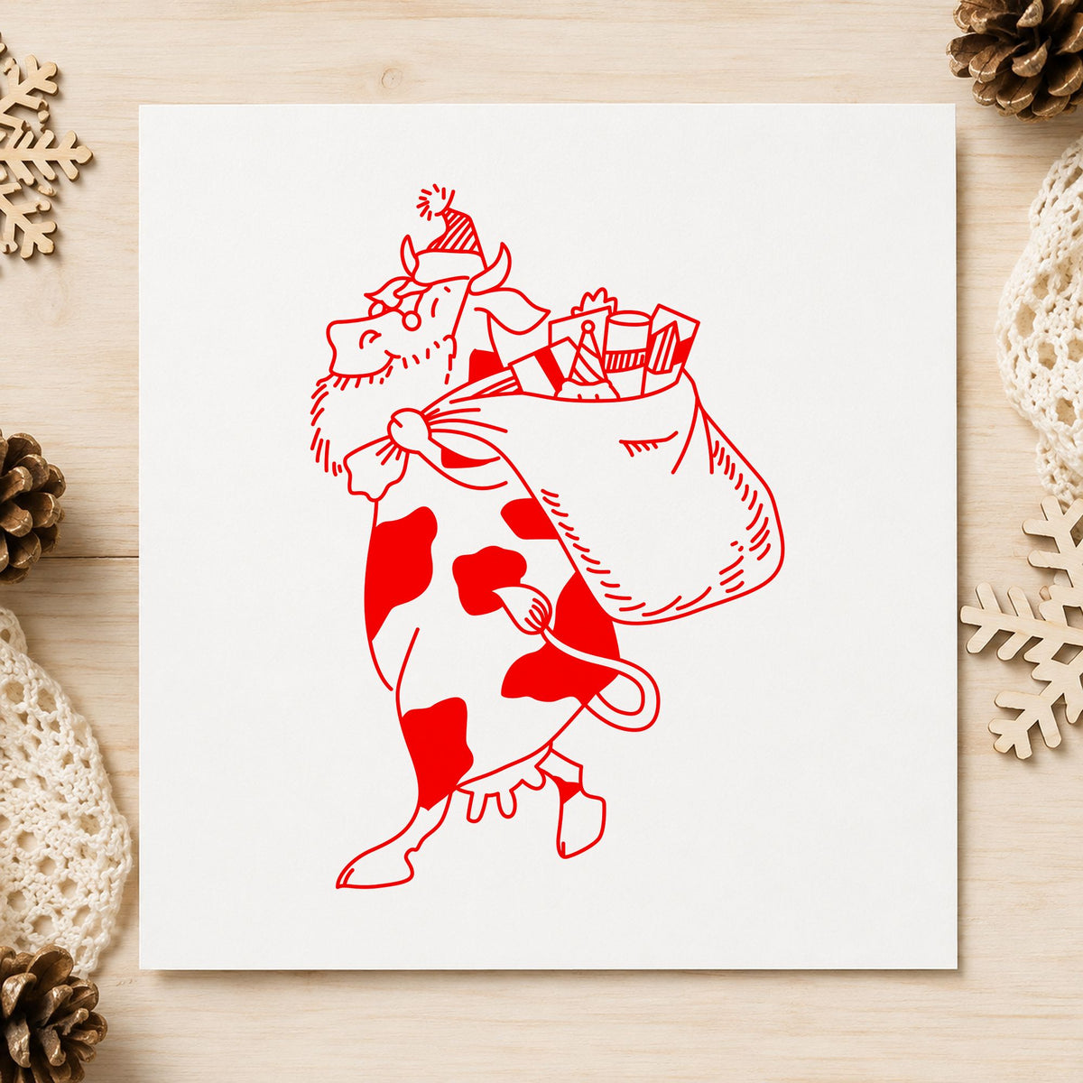 Santa Cow with Gift Sack Rubber Stamp Large impression in red ink on white paper in a styled craft setting.