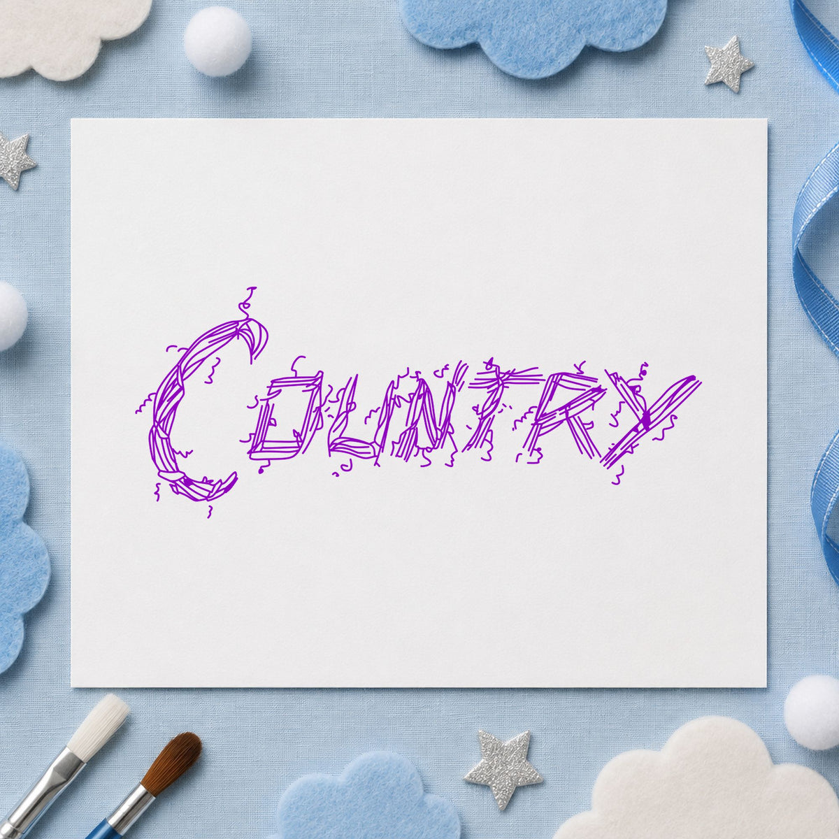 Country Lettering Rubber Stamp impression in purple ink on white paper in a styled craft setting.