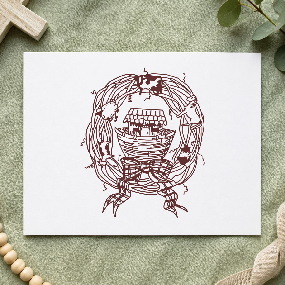 Ark in Wreath Rubber Stamp impression in brown ink on white paper in a styled craft setting.