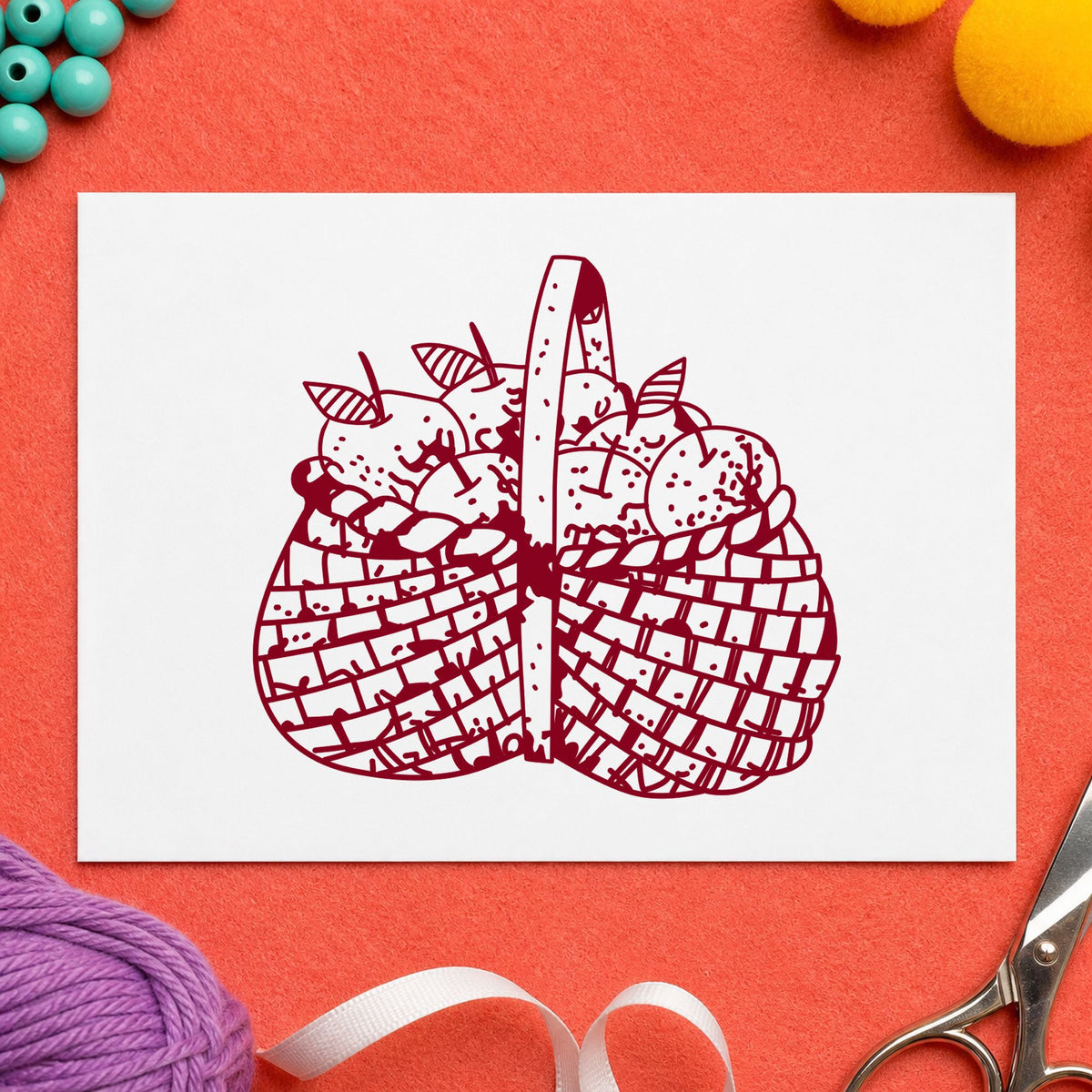 Basket Brimming with Apples Rubber Stamp impression in burgundy ink on white paper in a styled craft setting.