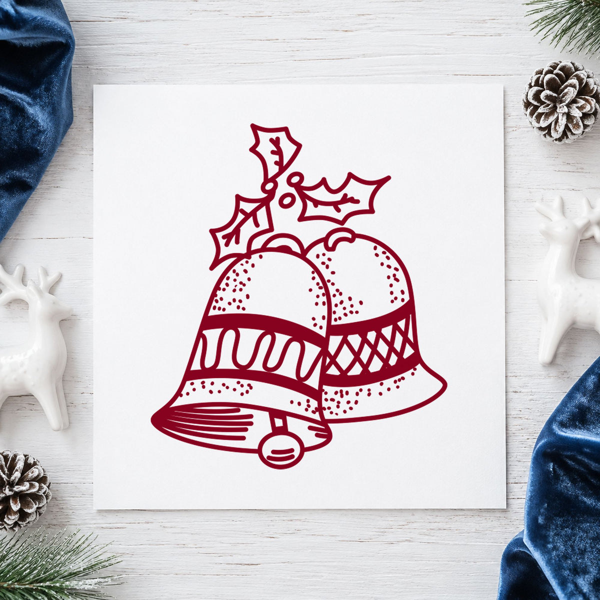 Christmas Bells with Mistletoe Rubber Stamp impression in burgundy ink on white paper in a styled craft setting.