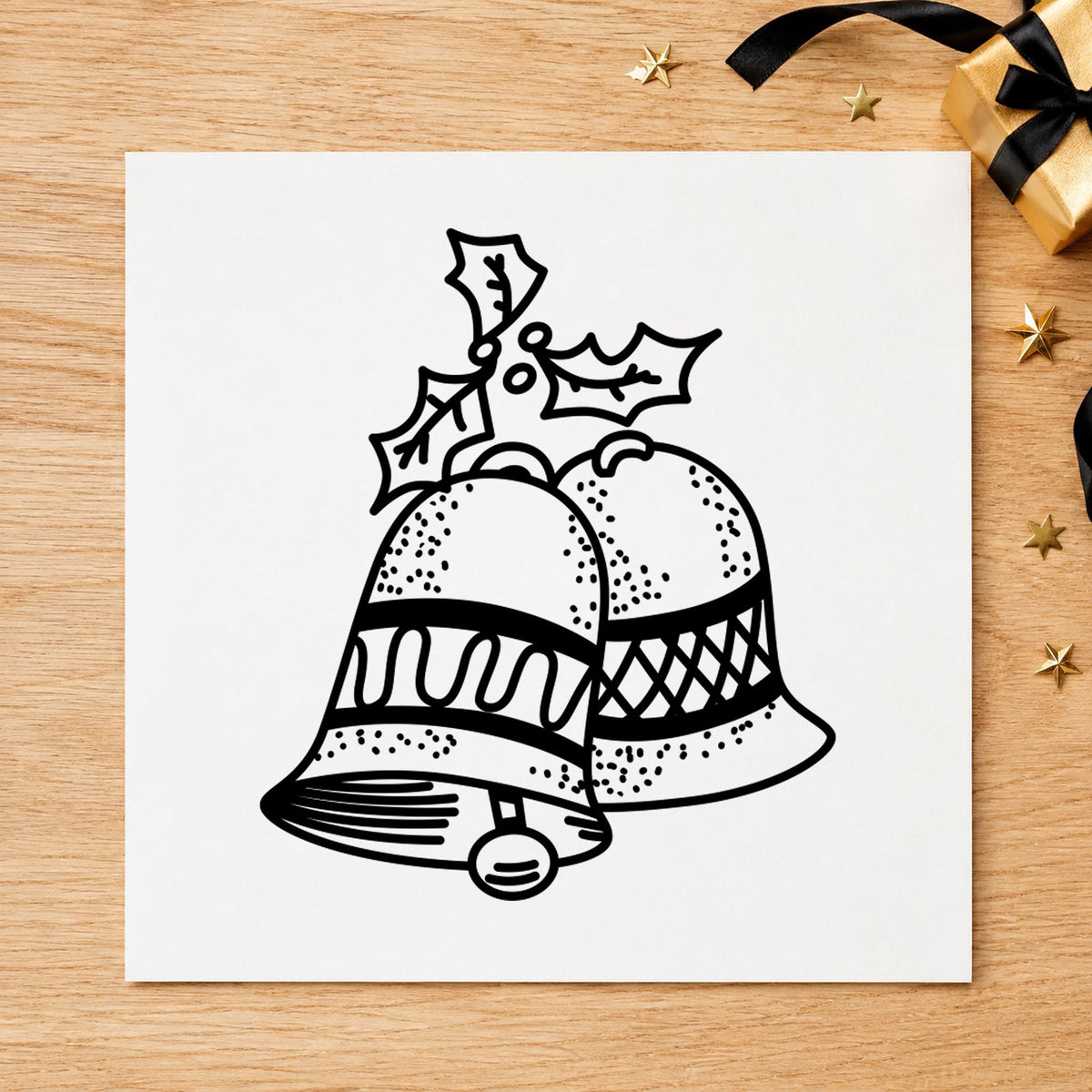 Black impression from a christmas bell stamp, featuring the christmas bells with mistletoe design on white paper.