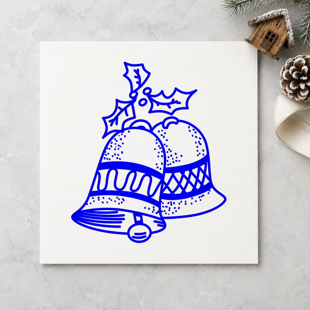 Christmas Bells with Mistletoe Rubber Stamp impression in blue ink on white paper in a styled craft setting.