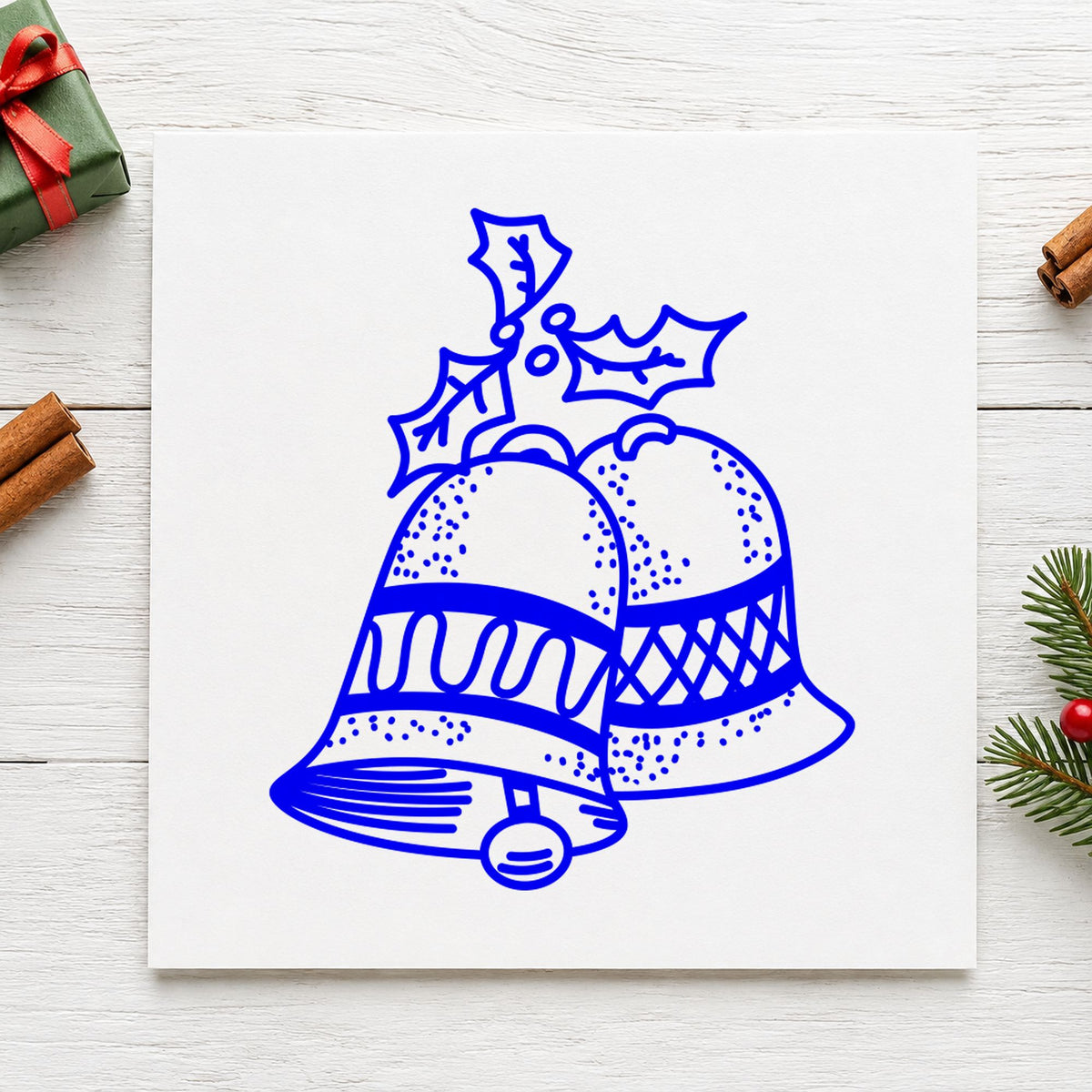 Blue holiday card making stamp impression featuring the christmas bells with mistletoe design on white paper.