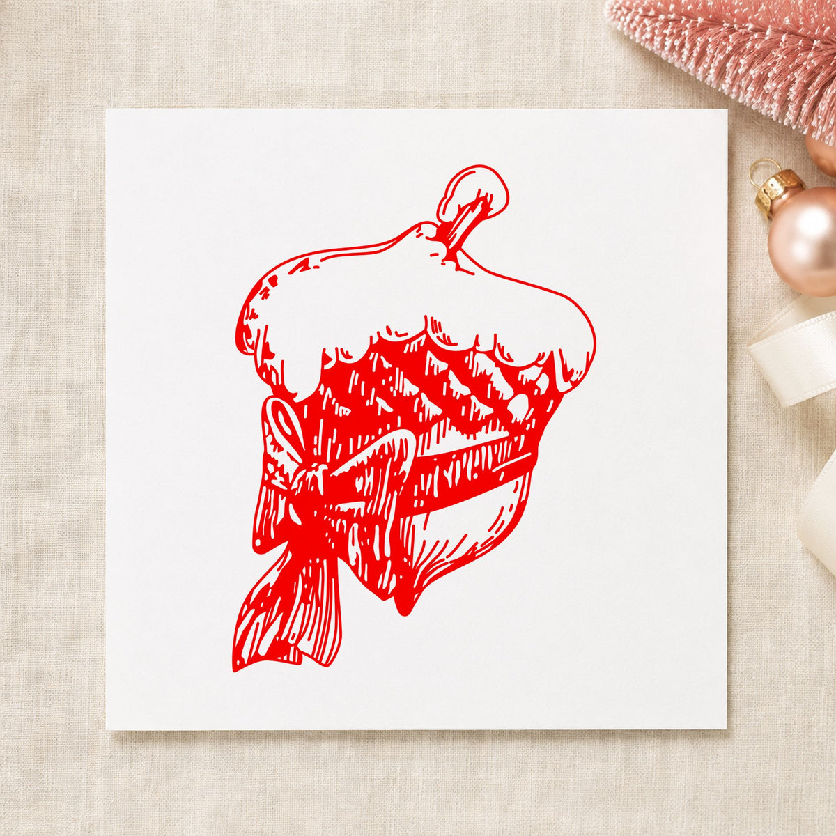 Snowy Acorn with Bow Christmas Rubber Stamp impression in red ink on white paper in a styled craft setting.