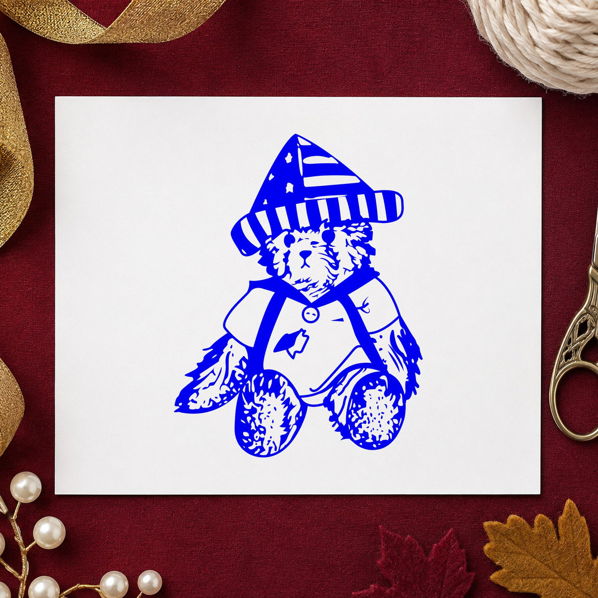 Bear in Stars and Stripes Hat Rubber Stamp impression in blue ink on white paper in a styled craft setting.
