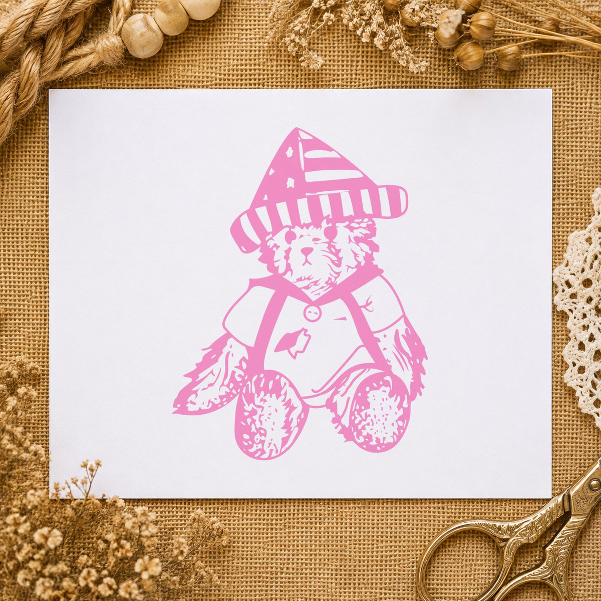 Bear in Stars and Stripes Hat Rubber Stamp impression in pink ink on white paper in a styled craft setting.