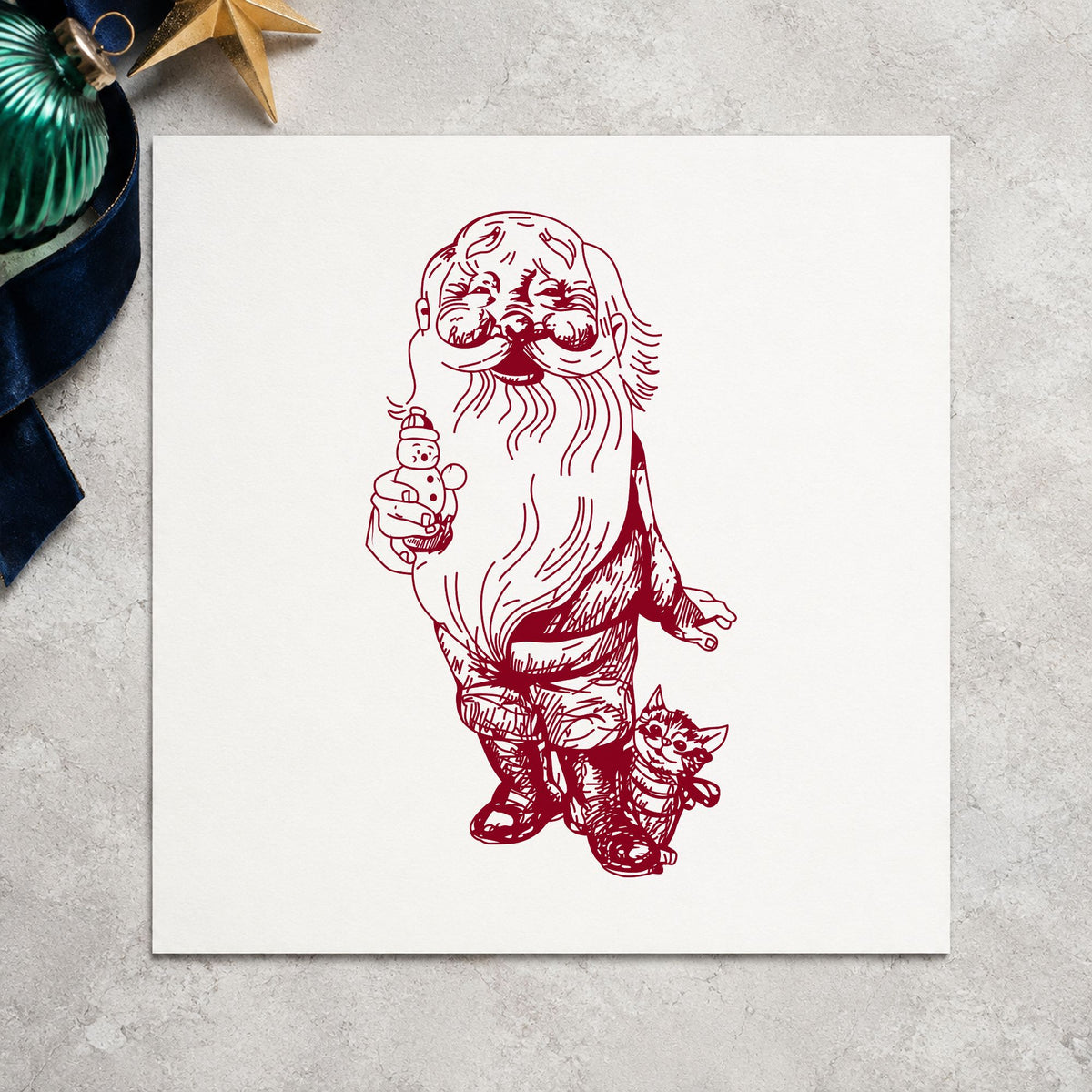 Santa with Kitten and Snowman Rubber Stamp impression in burgundy ink on white paper in a styled craft setting.
