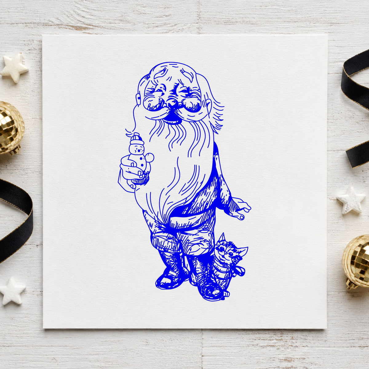 Santa with Kitten and Snowman Rubber Stamp impression in blue ink on white paper in a styled craft setting.