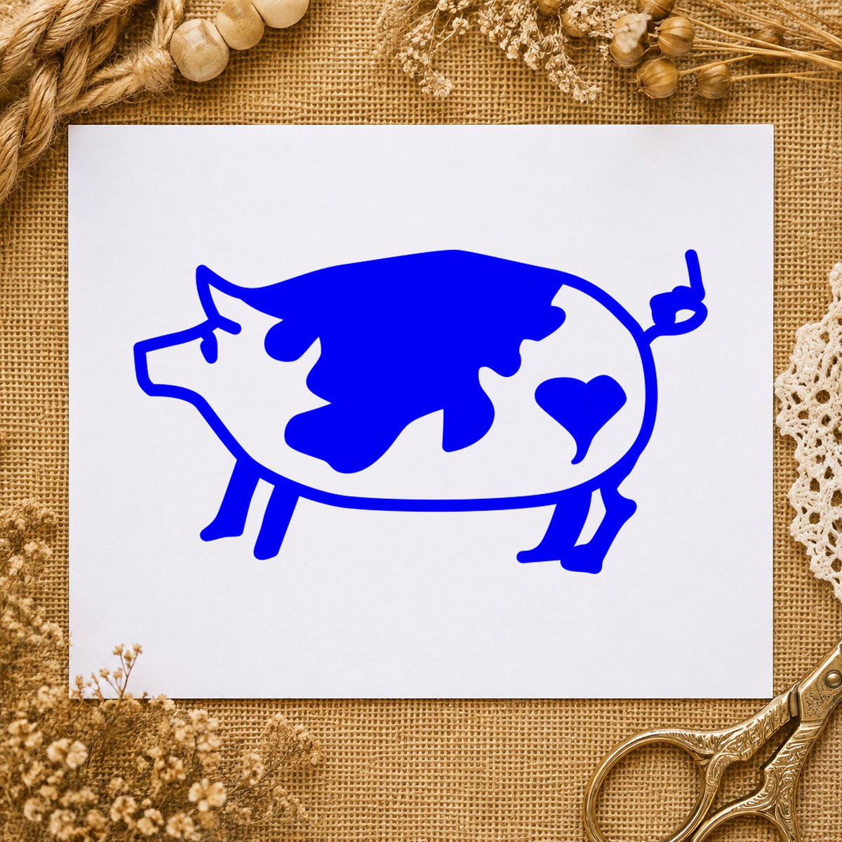 Spotted Pig with Heart Rubber Stamp impression in blue ink on white paper in a styled craft setting.