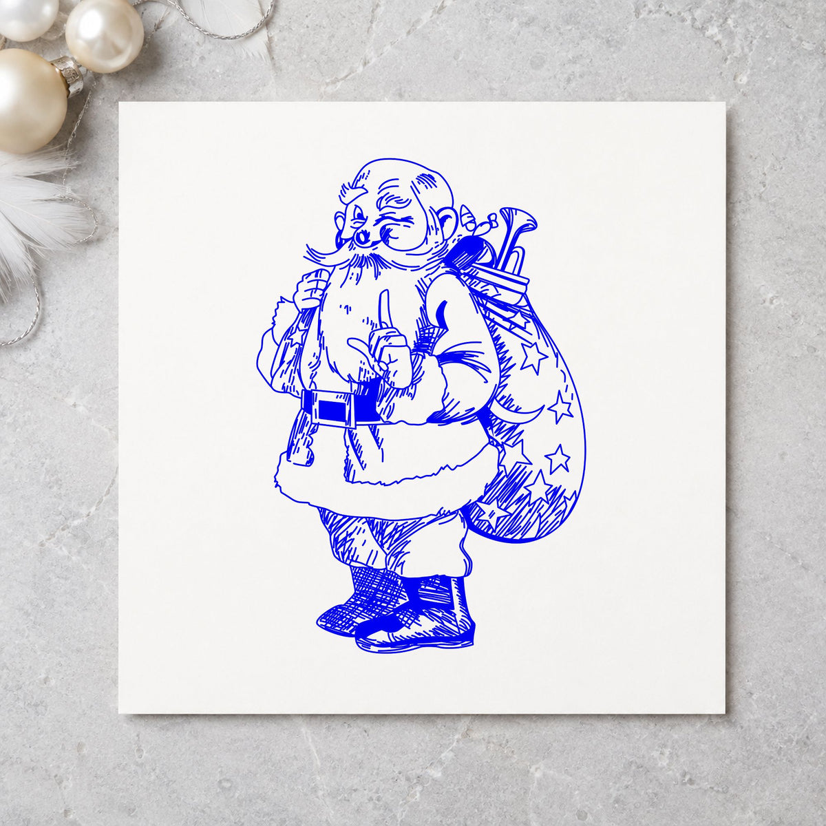 Santa with Gift Sack Rubber Stamp impression in blue ink on white paper in a styled craft setting.