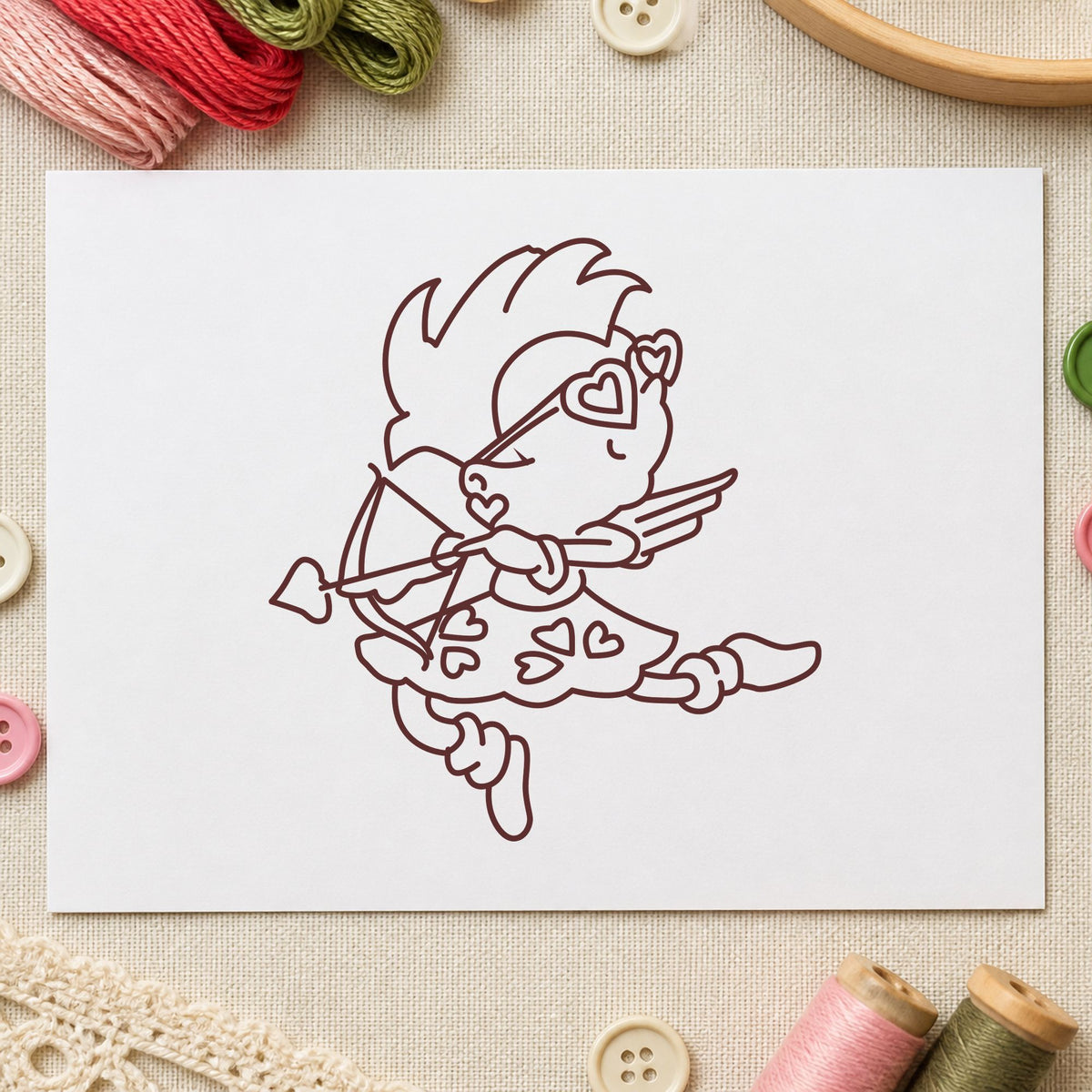 Cupid with Heart Sunglasses Rubber Stamp impression in brown ink on white paper in a styled craft setting.