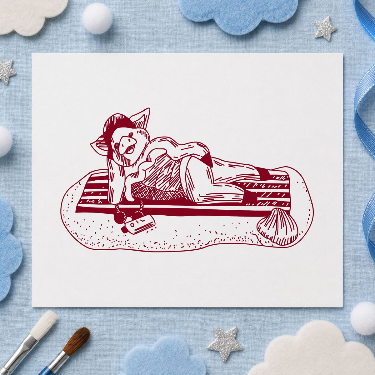 Pig on Beach Blanket Rubber Stamp impression in burgundy ink on white paper in a styled craft setting.