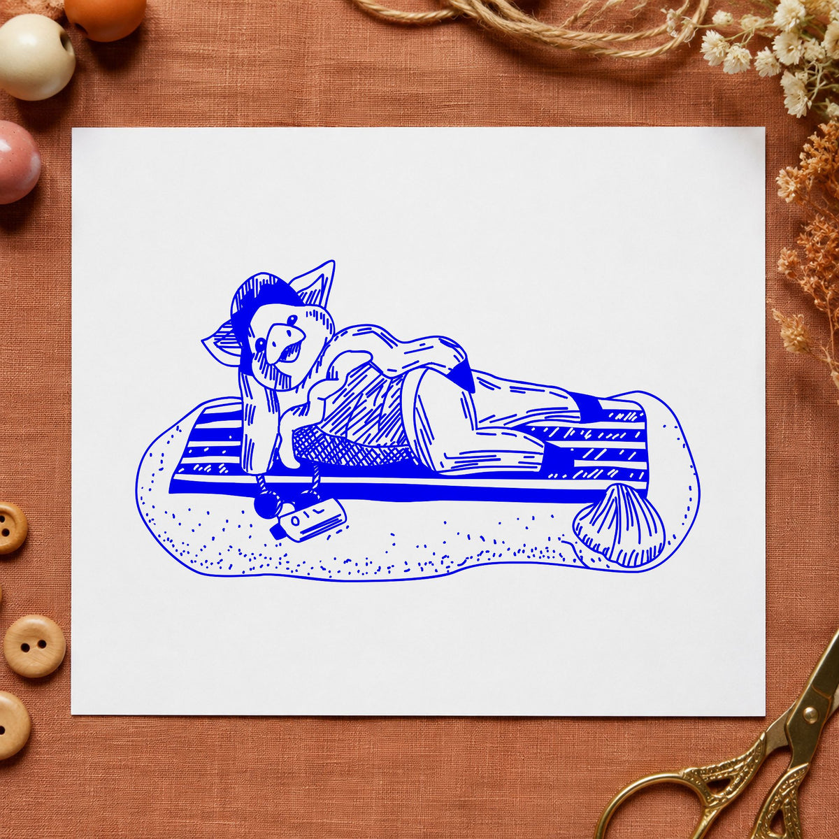 Pig on Beach Blanket Rubber Stamp impression in blue ink on white paper in a styled craft setting.