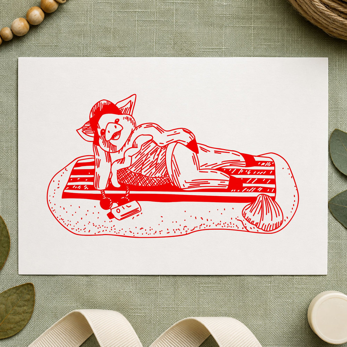 Pig on Beach Blanket Rubber Stamp impression in red ink on white paper in a styled craft setting.
