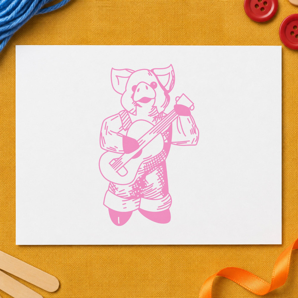 Banjo Playing Pig Rubber Stamp impression in pink ink on white paper in a styled craft setting.