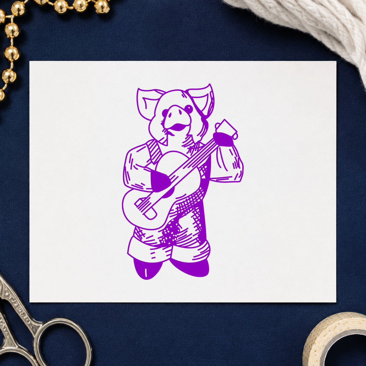 Banjo Playing Pig Rubber Stamp impression in purple ink on white paper in a styled craft setting.