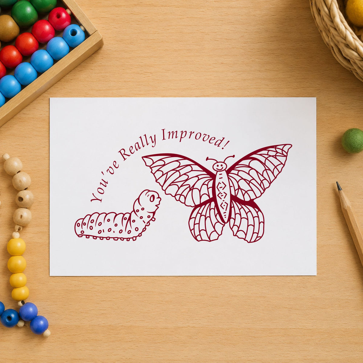 Youve Really Improved Butterfly and Caterpillar Rubber Stamp impression in burgundy ink on white paper in a styled craft setting.