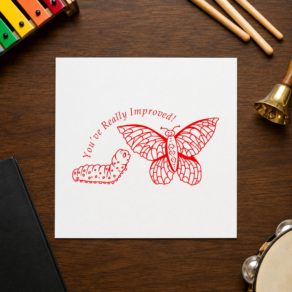 Youve Really Improved Butterfly and Caterpillar Rubber Stamp impression in red ink on white paper in a styled craft setting.
