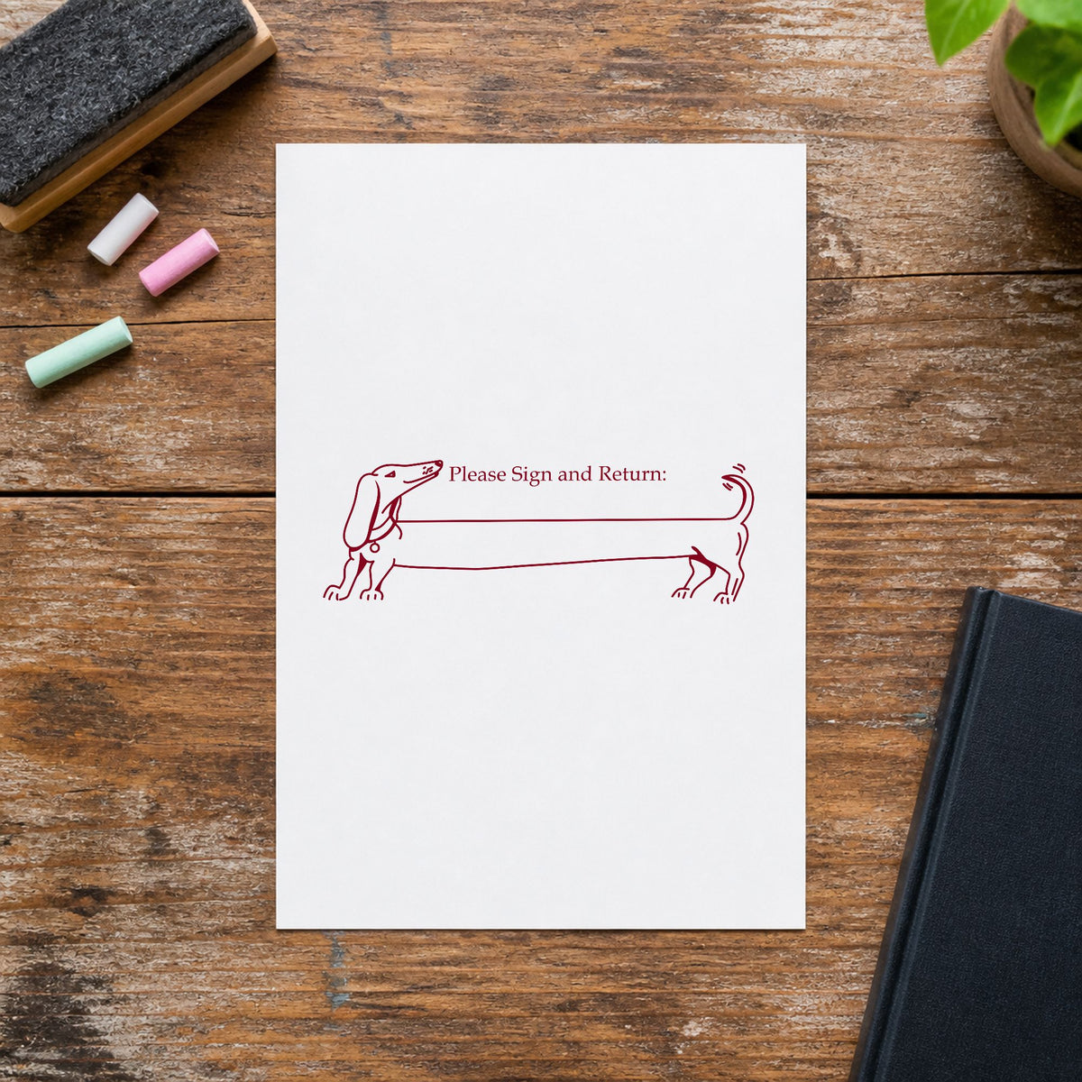 Please Sign and Return Dog Rubber Stamp impression in burgundy ink on white paper in a styled craft setting.