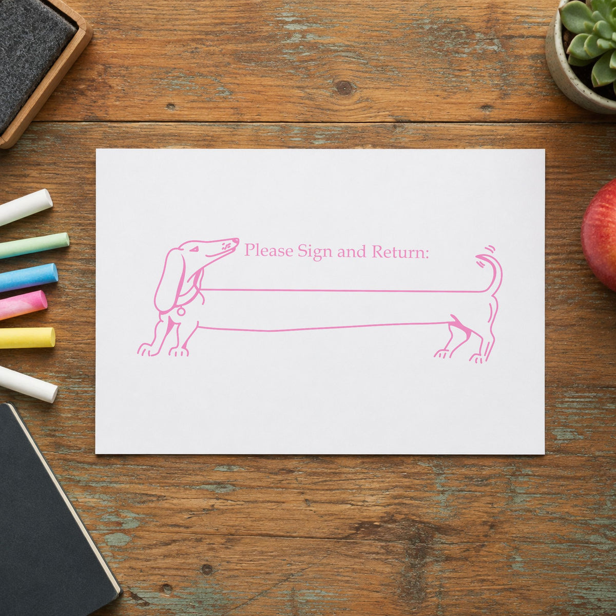 Please Sign and Return Dog Rubber Stamp impression in pink ink on white paper in a styled craft setting.