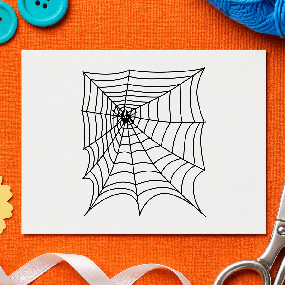 Black impression from a spiderweb rubber stamp, featuring the spider and web halloween design on white paper.