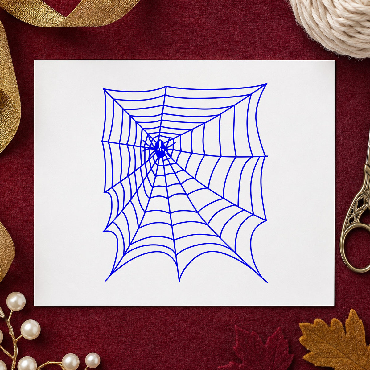 Blue halloween craft stamp impression featuring the spider and web halloween design on white paper.