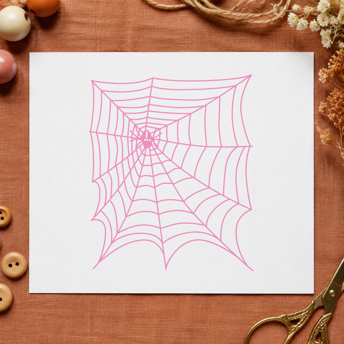 Spider and Web Halloween Rubber Stamp impression in pink ink on white paper in a styled craft setting.