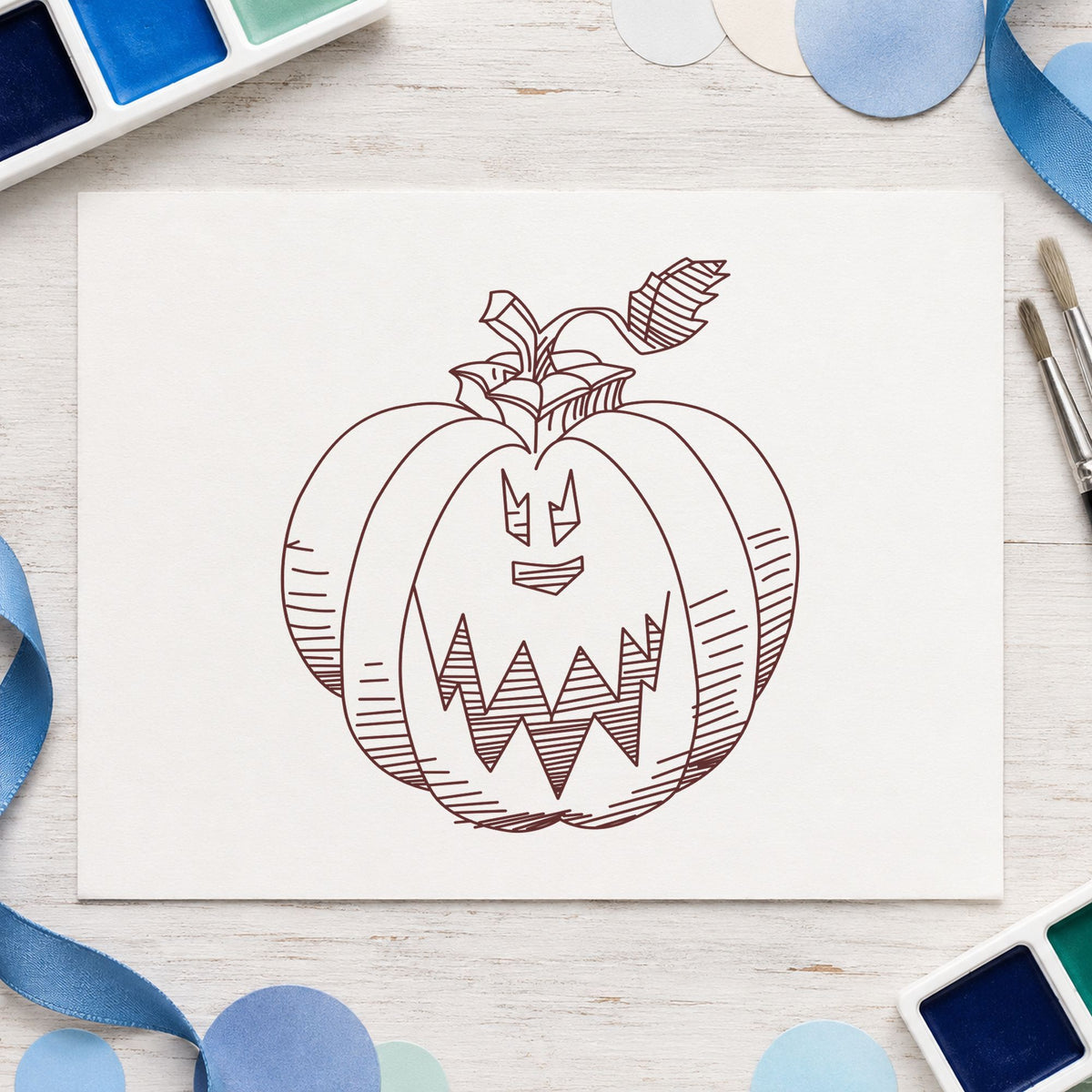 Scary Pumpkin Face Rubber Stamp impression in brown ink on white paper in a styled craft setting.