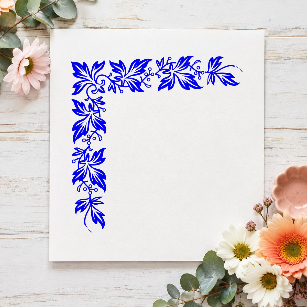 Blue botanical corner stamp impression featuring the semi solid leaf corner design on white paper.