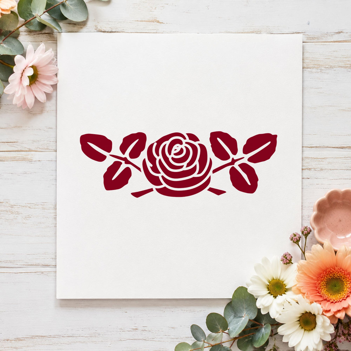 Rose with Leaves Rubber Stamp Small impression in burgundy ink on white paper in a styled craft setting.