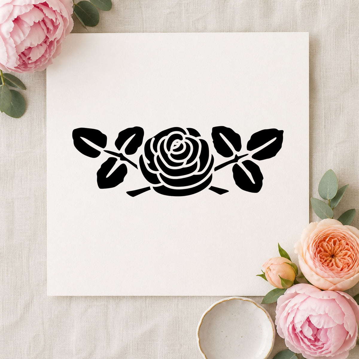 Black impression from a rose rubber stamp, featuring the rose with leaves small design on white paper.