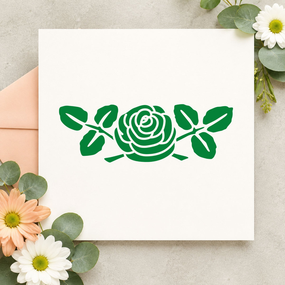 Rose with Leaves Rubber Stamp Small impression in green ink on white paper in a styled craft setting.