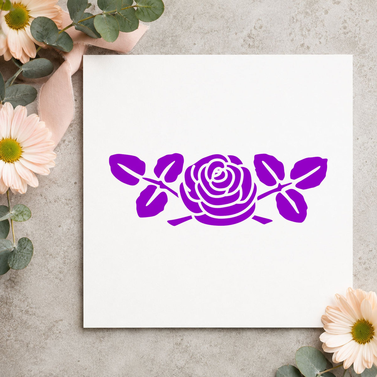 Rose with Leaves Rubber Stamp Small impression in purple ink on white paper in a styled craft setting.