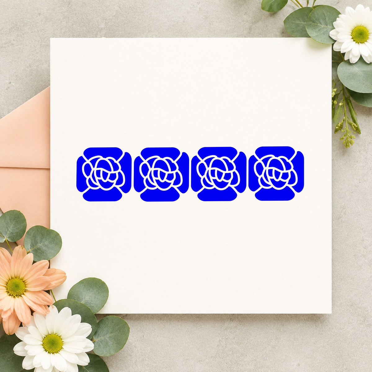 Four Solid Flowers Border Rubber Stamp impression in blue ink on white paper in a styled craft setting.