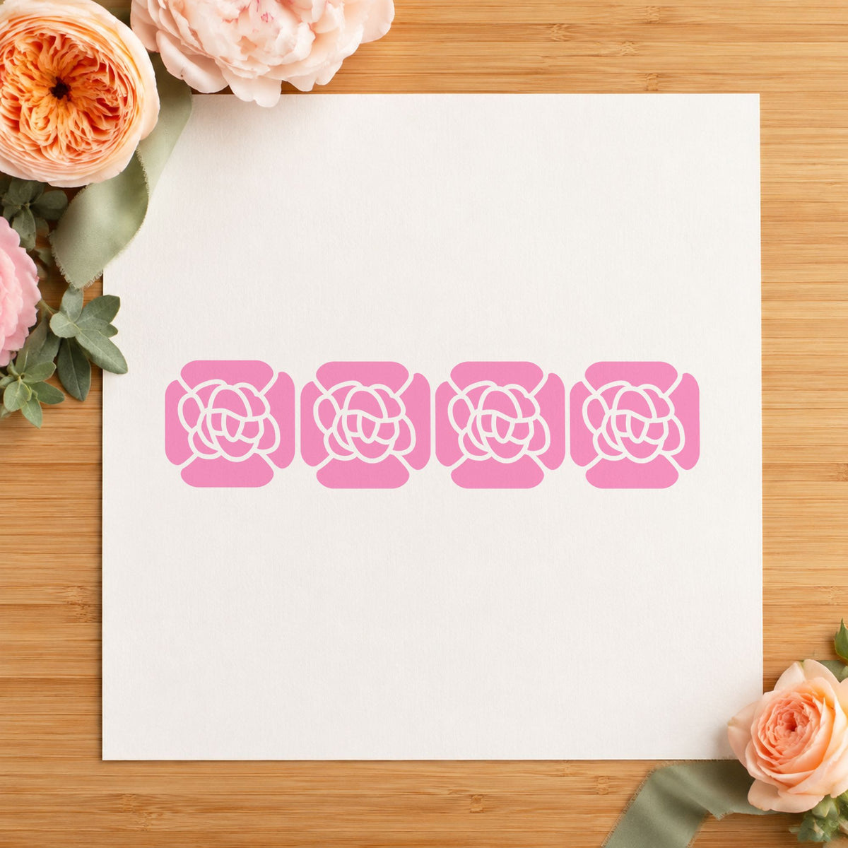 Four Solid Flowers Border Rubber Stamp impression in pink ink on white paper in a styled craft setting.