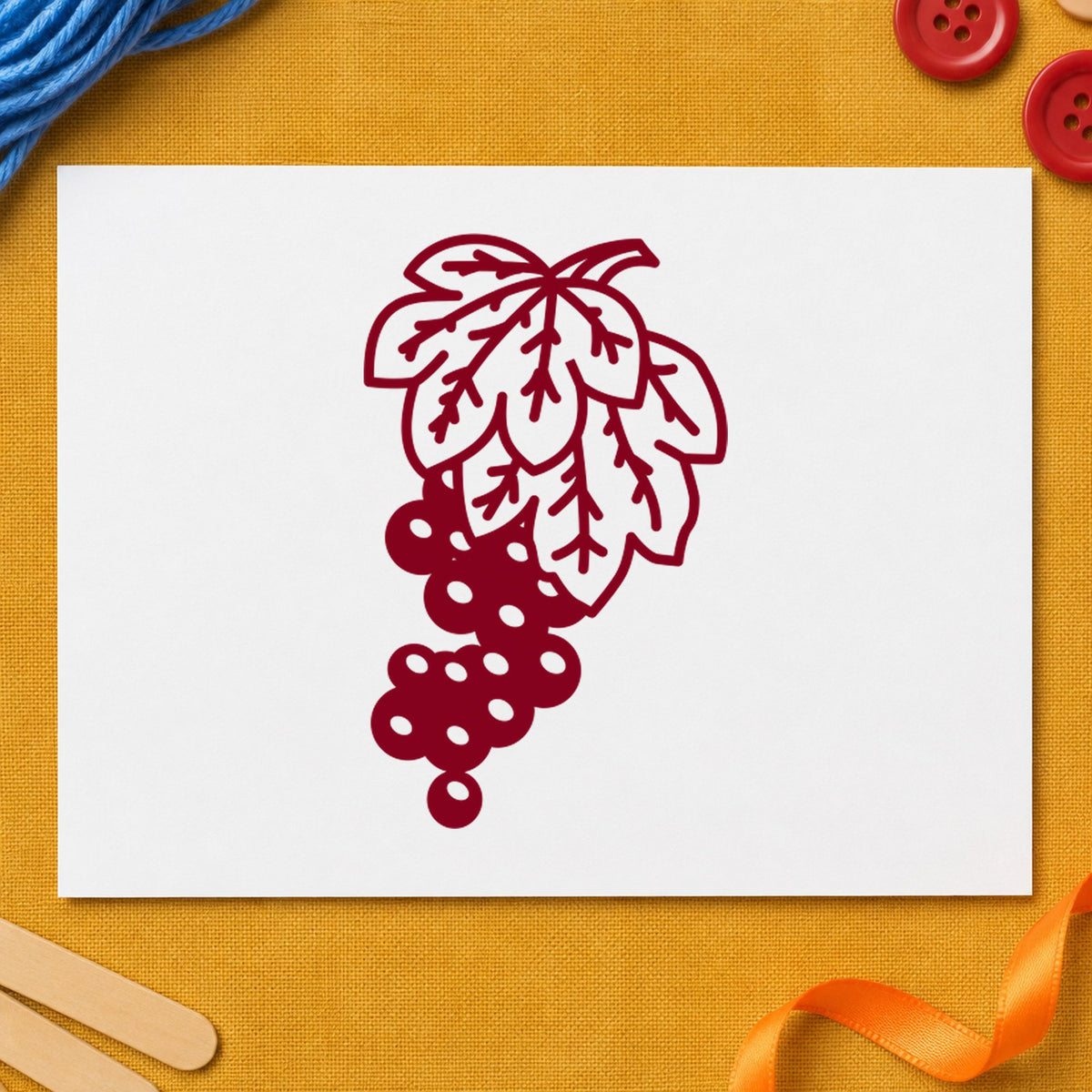 Grape Bunch on Vine Rubber Stamp impression in burgundy ink on white paper in a styled craft setting.