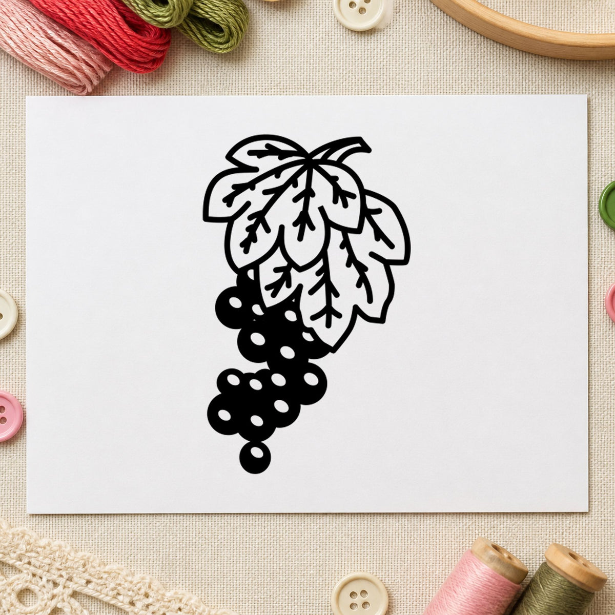 Black impression from a grape rubber stamp, featuring the grape bunch on vine design on white paper.