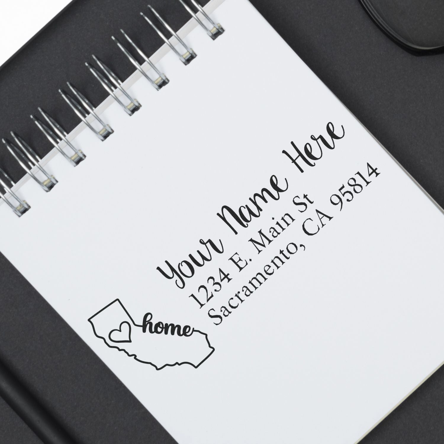 Custom return address rubber stamp impression on notebook, featuring a California home design and personalized mailing address.