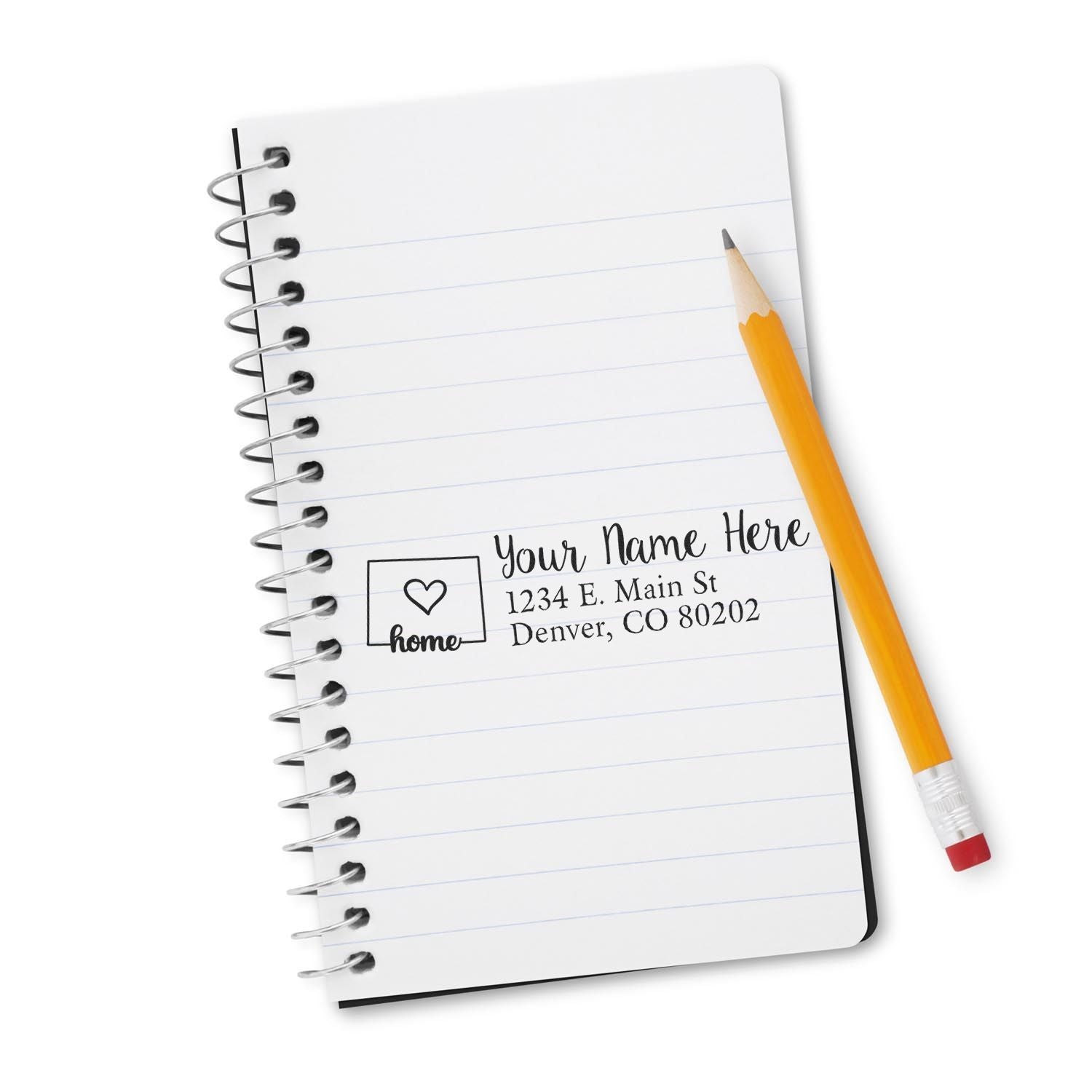 Personalized address rubber stamp on notebook with pencil, showing name, home icon and mailing address for custom return stamps.