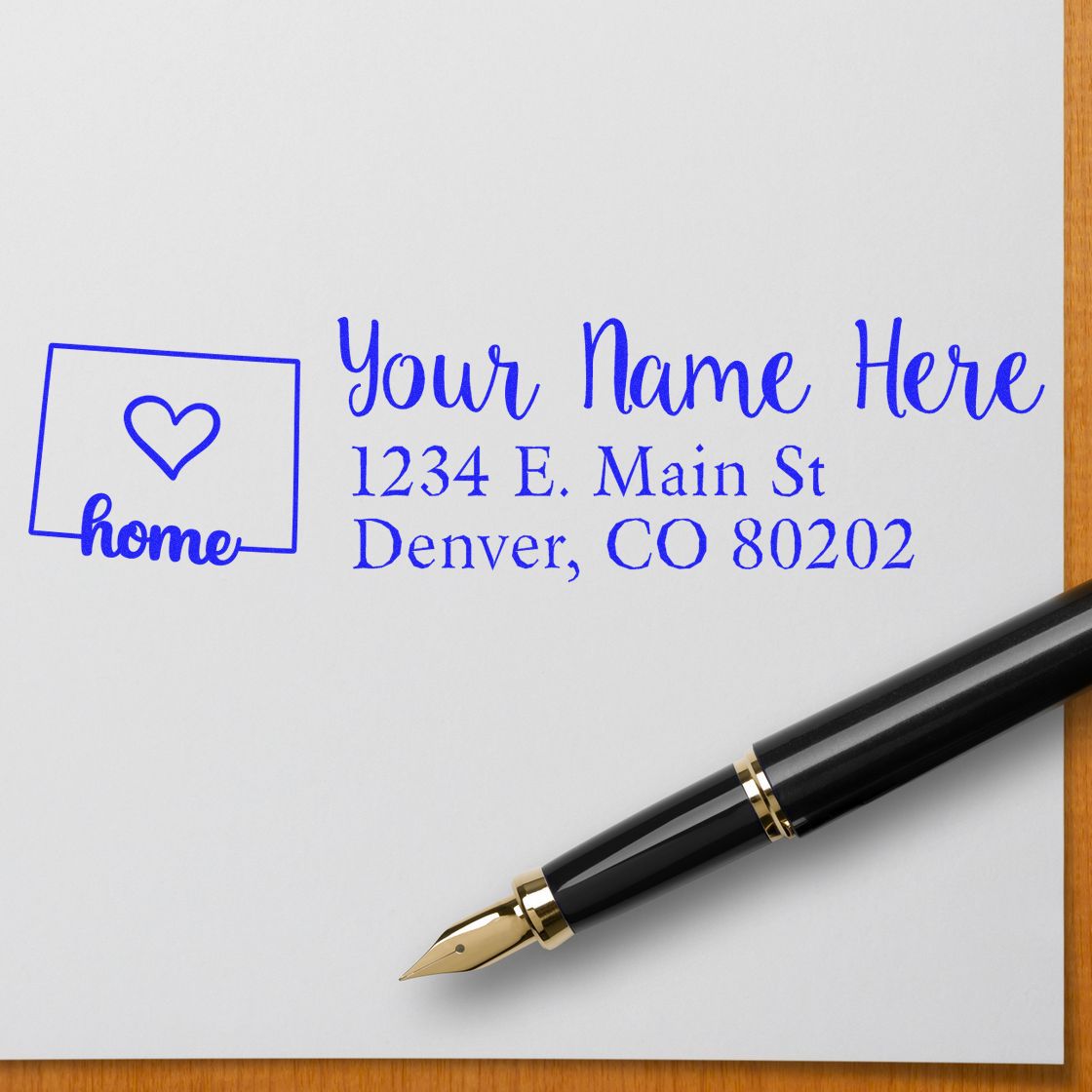Personalized rubber stamp with home icon and return address, featuring custom name, Denver address, and fountain pen on paper.