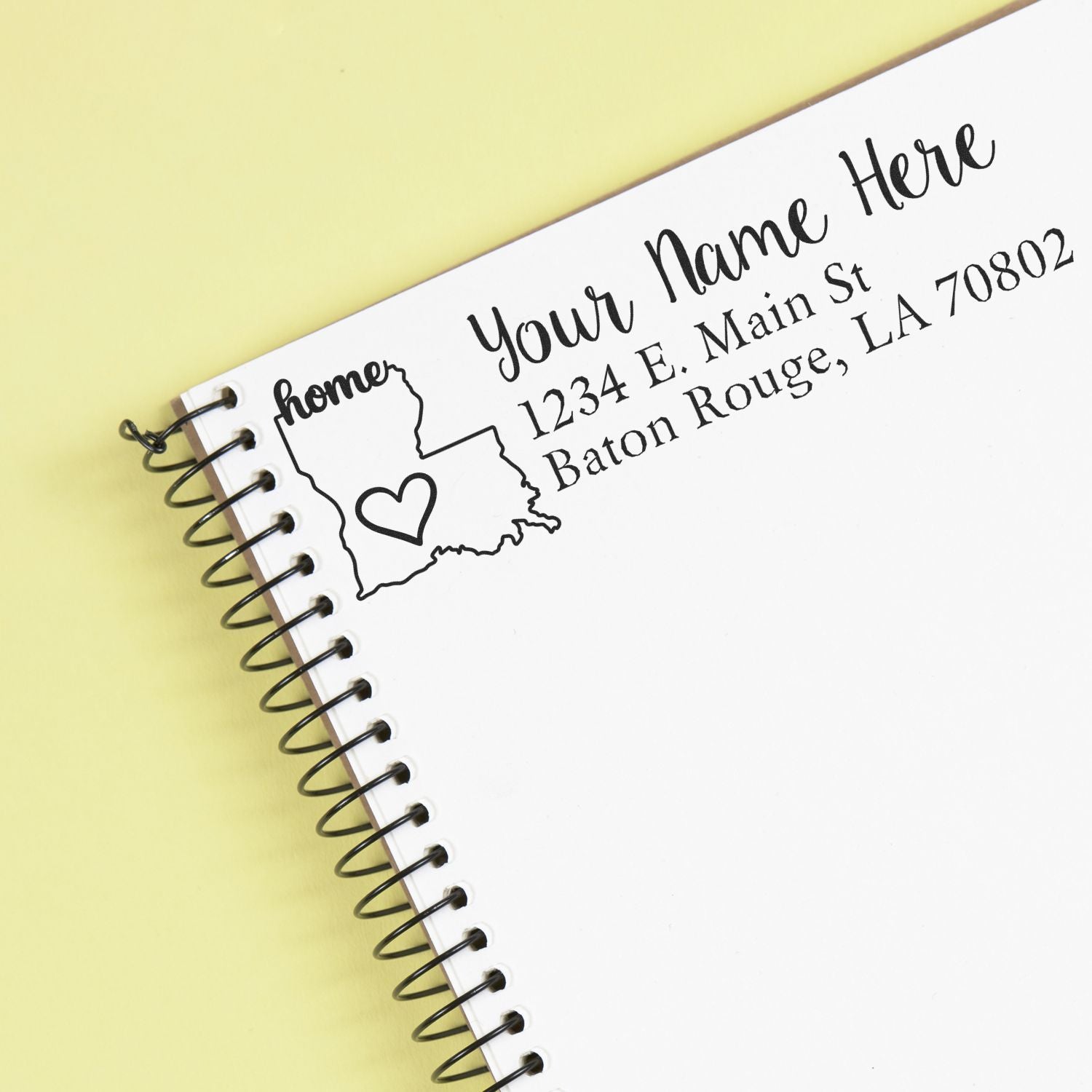 Custom rubber return address stamp with Louisiana outline and heart design on a spiral notebook
