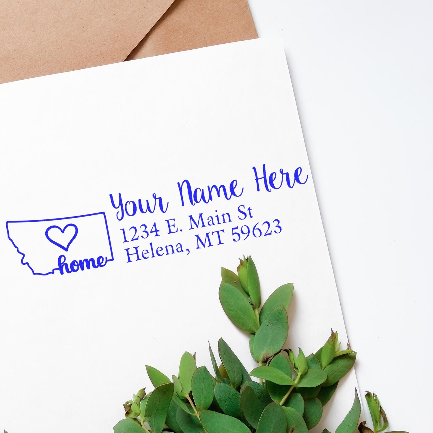 Custom Montana return address rubber stamp with home icon, name placeholder, and blue ink on white envelope.