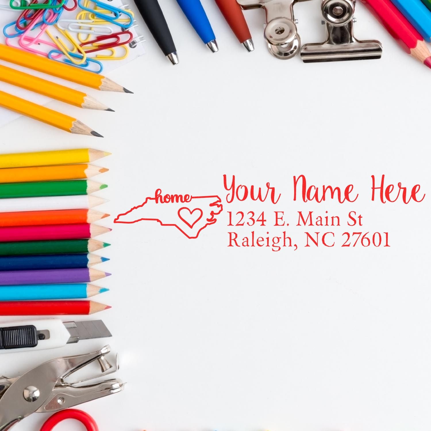 Personalized rubber address stamp with North Carolina outline, shown with office supplies for custom home or business branding.
