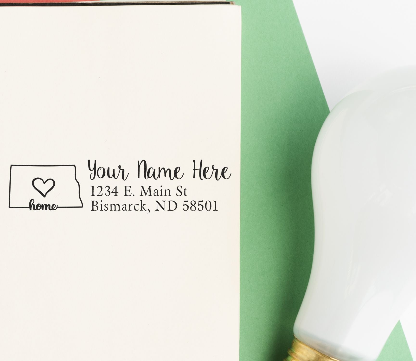 Personalized return address rubber stamp with home icon, imprinting name and address on a notebook page.