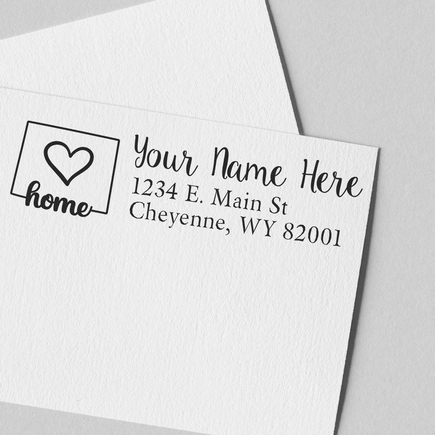 Custom return address rubber stamp with heart home logo and personalized name and address on white paper.