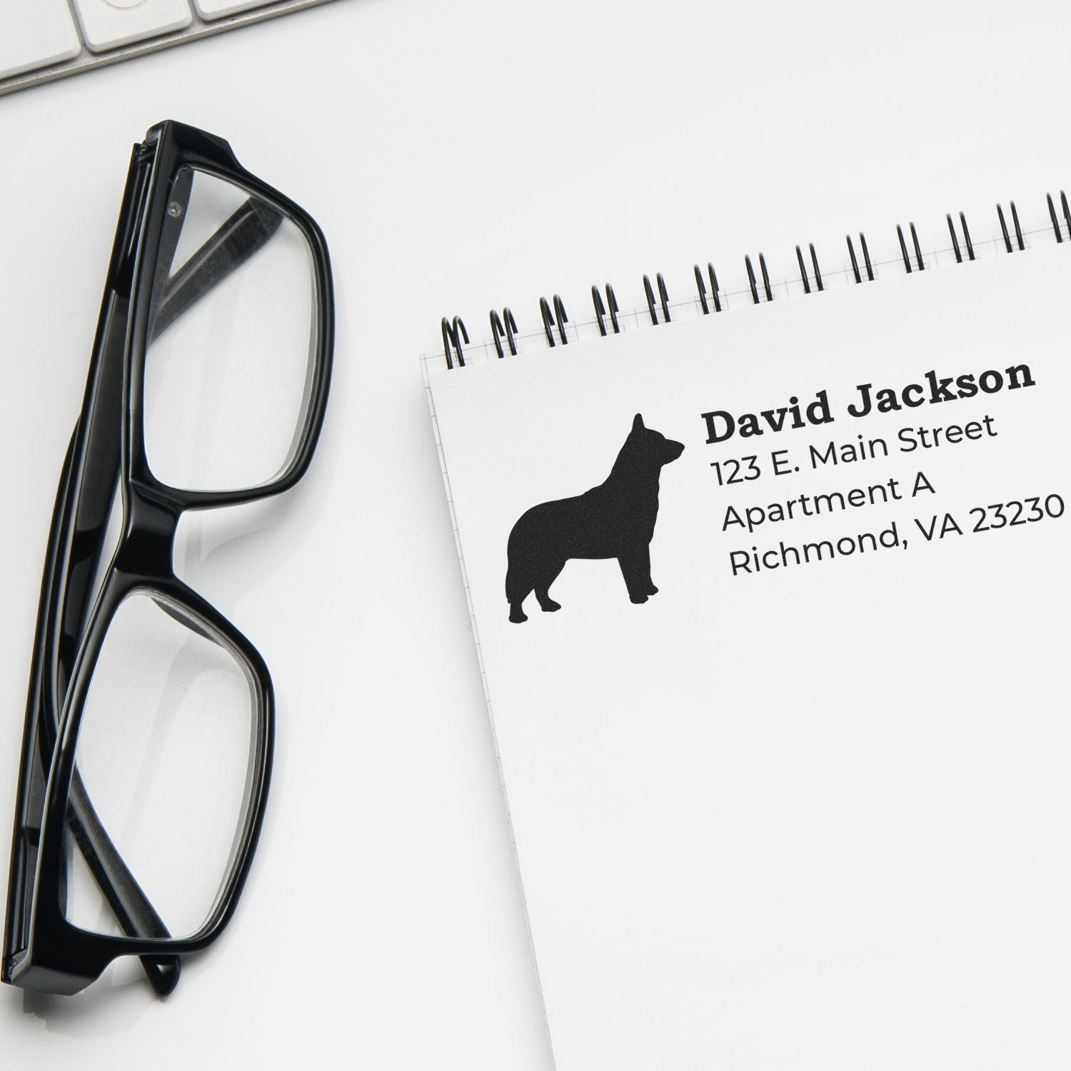 Custom dog return address rubber stamp beside eyeglasses and notebook for personalized stationery and mailing envelopes.