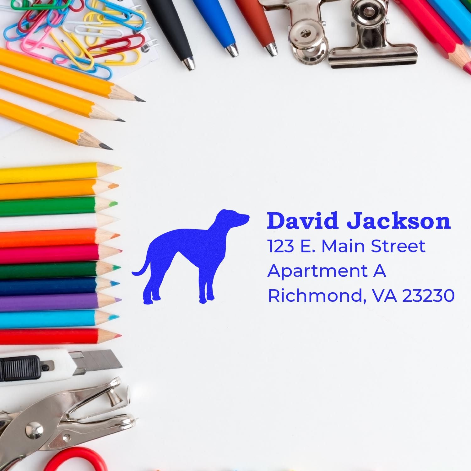 Custom address rubber stamp with dog logo, name and mailing address, shown with stationery and office supplies.