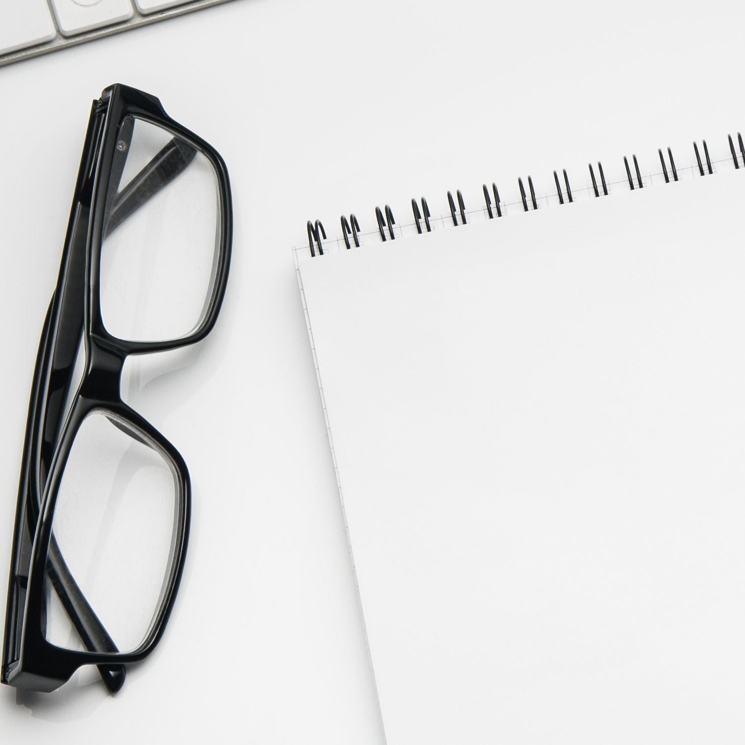 Eyeglasses and blank spiral notebook on office desk for custom rubber stamp planning
